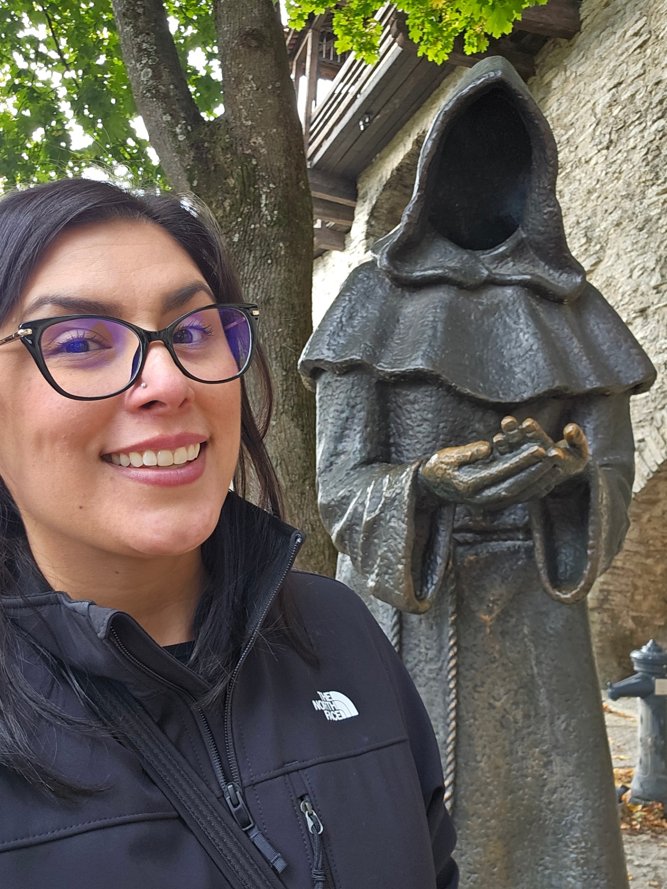 Woman beside the hooded monk statue in Tallinn