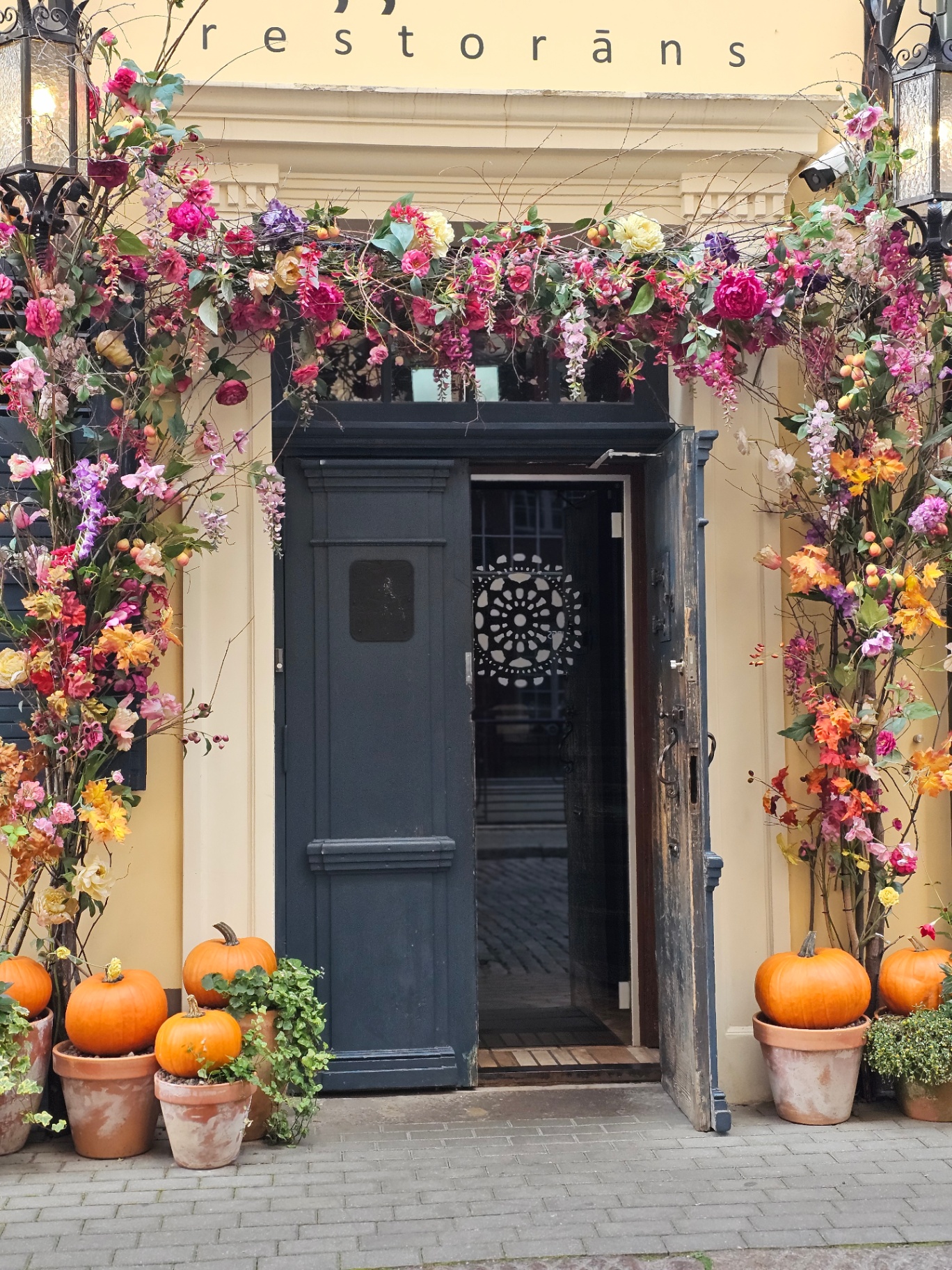 Restaurant doorway in Riga covered in flowers and pumpkins
