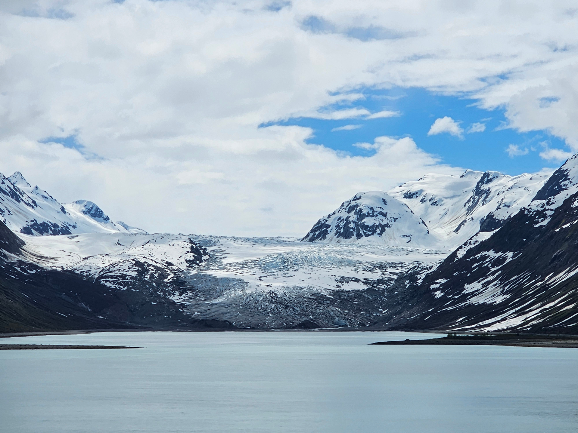 Glacier meeting still water between snow-covered mountains