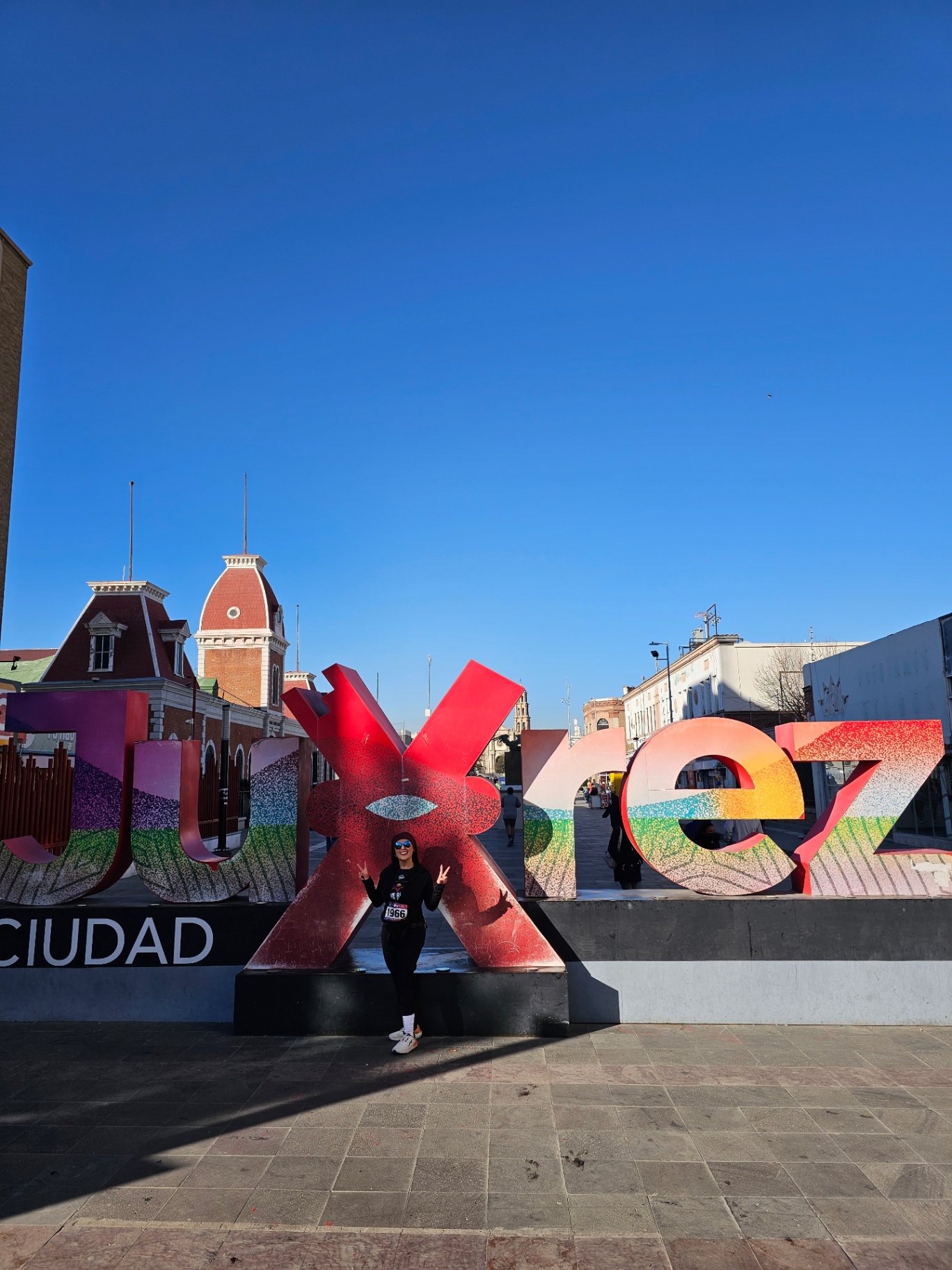 Woman posing in front of the colorful Ciudad Juárez letters sign