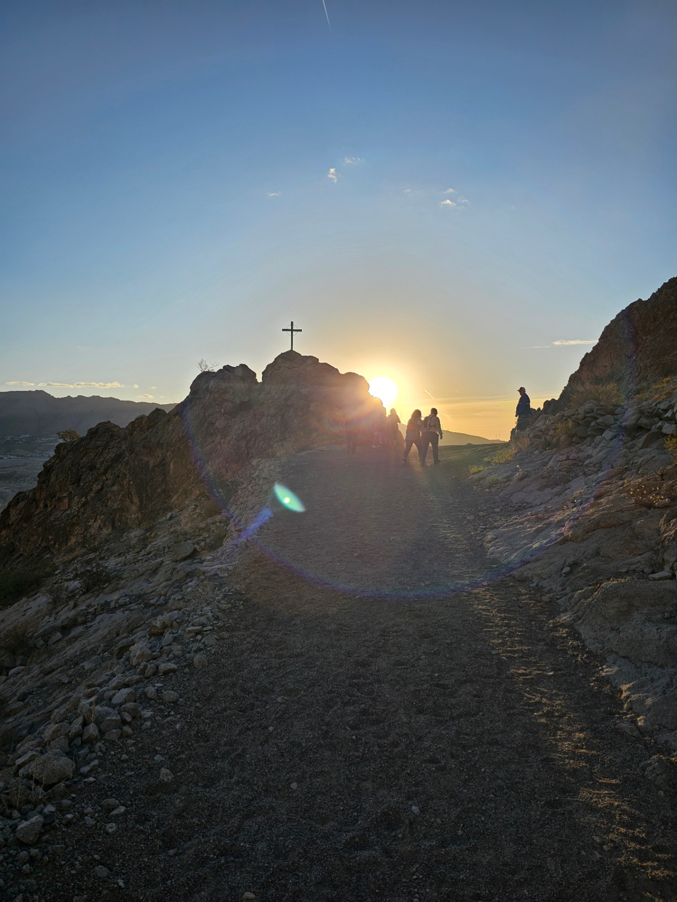 Hikers at a summit cross at sunrise