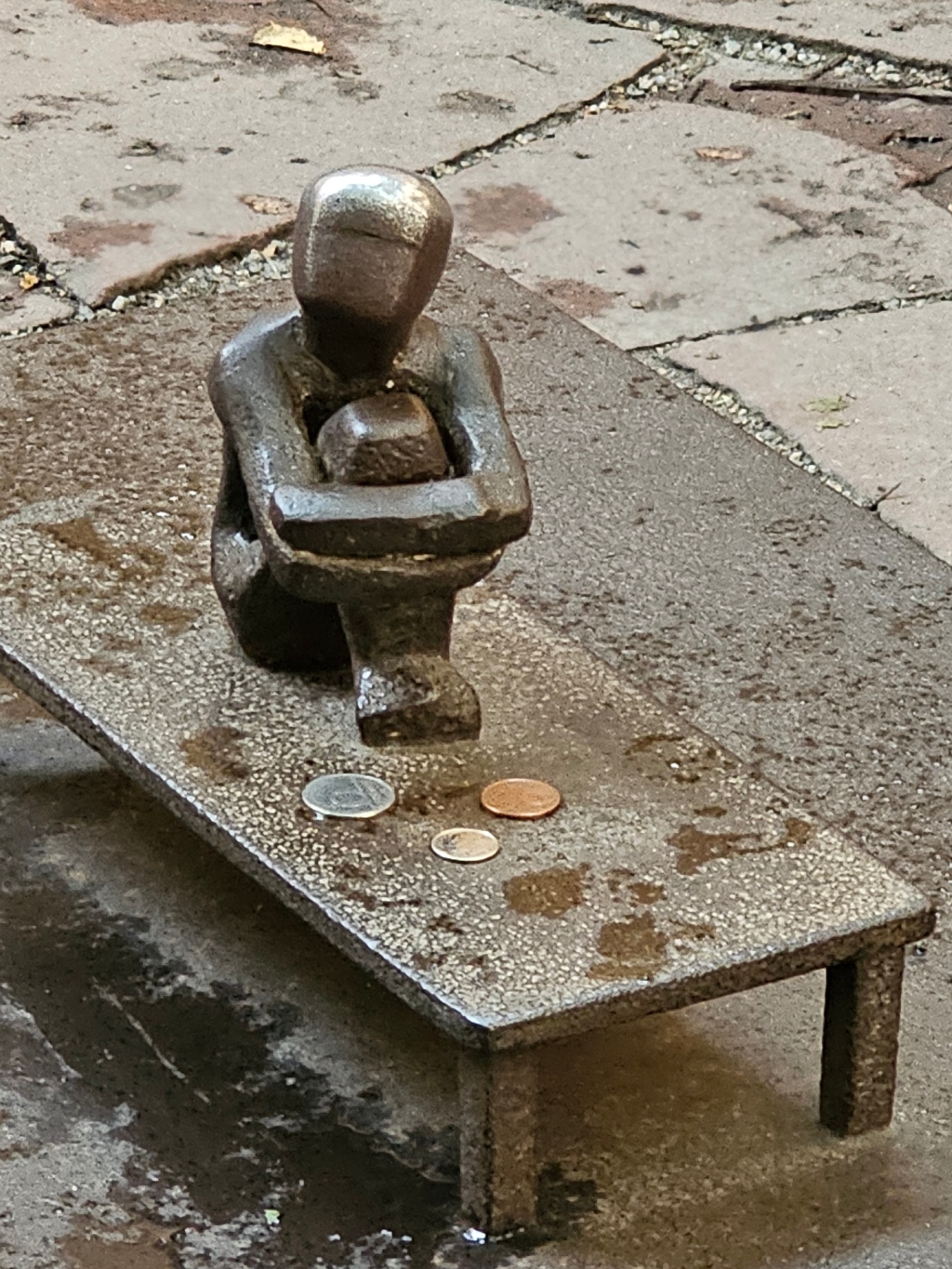 Small iron boy statue in Stockholm with coins