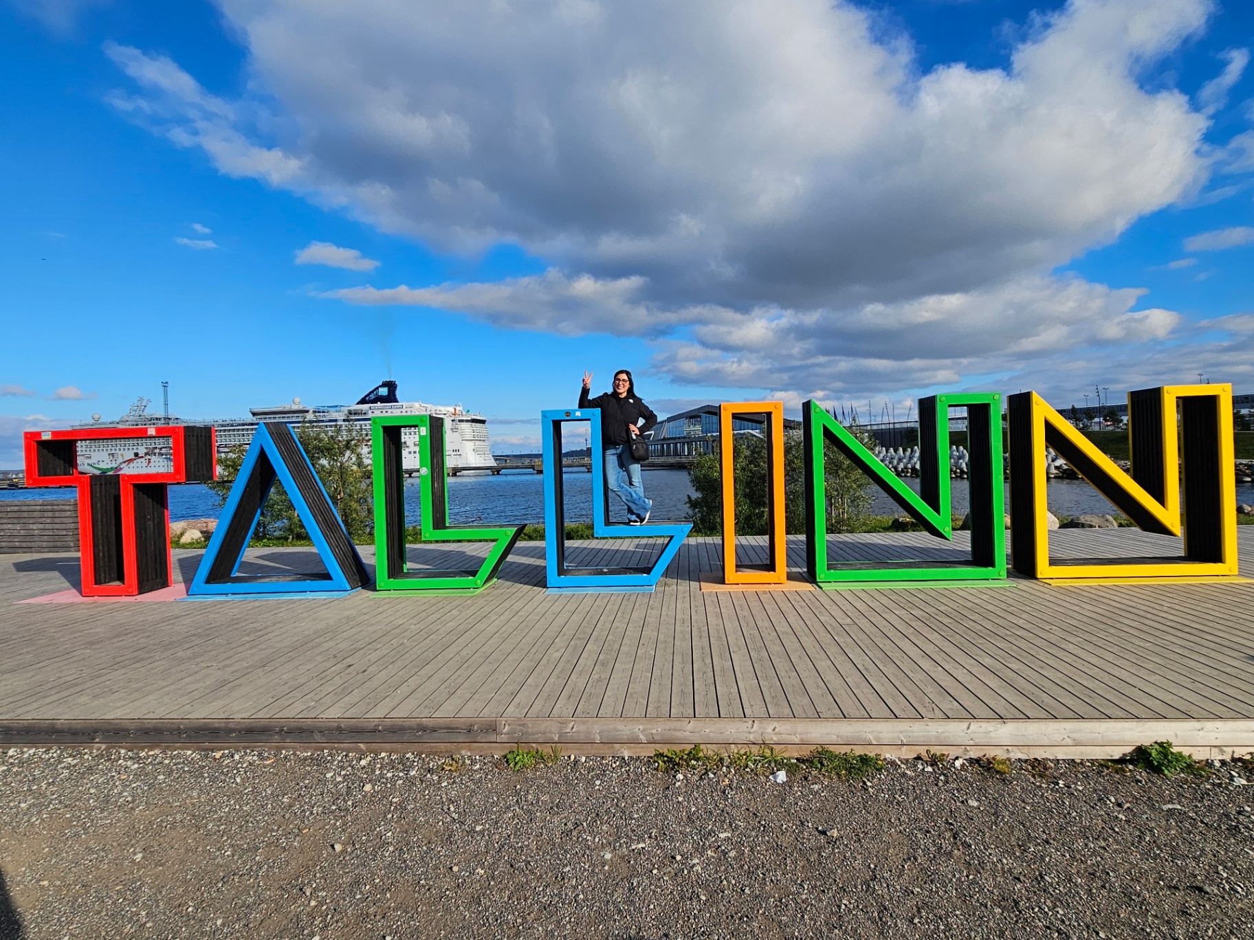 Woman at the colorful Tallinn sign by the harbor