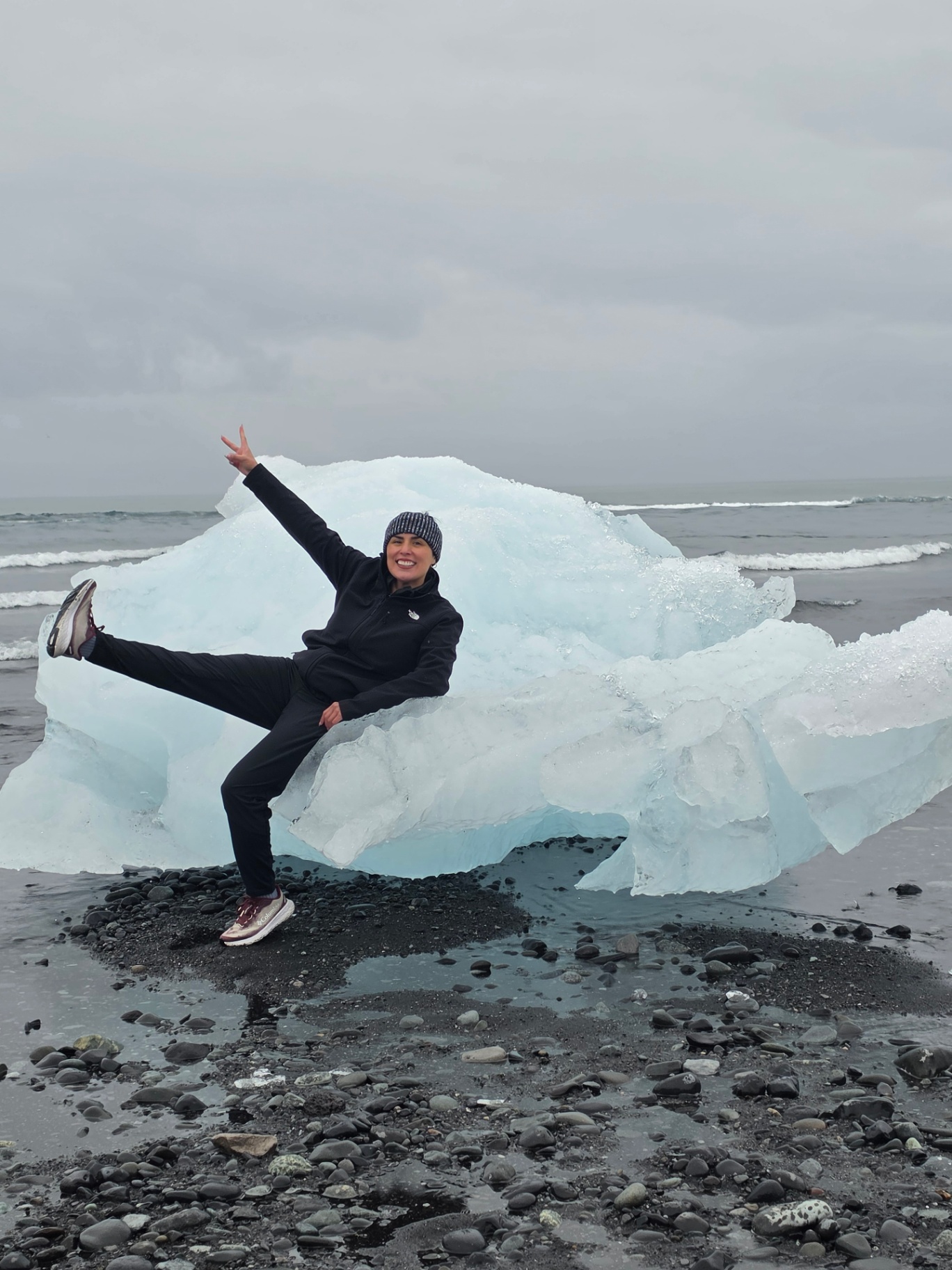 Woman posing beside an iceberg on Iceland's black sand Diamond Beach